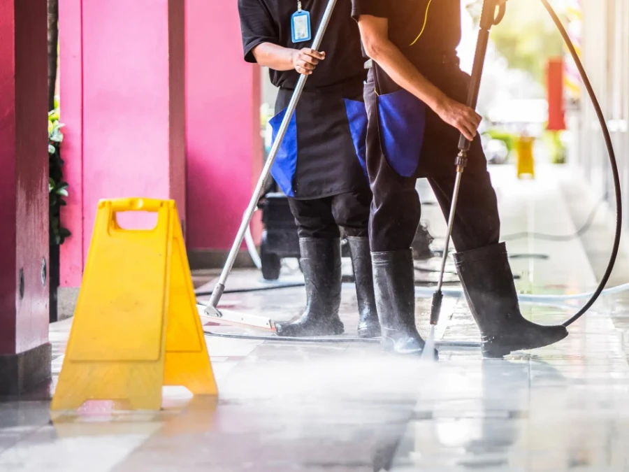Professional house cleaning Fort Myers team pressure washing commercial floor with wet floor sign