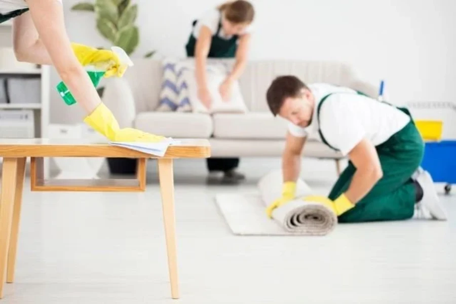 House cleaning Fort Myers team doing move-out cleaning, wiping table and rolling carpet