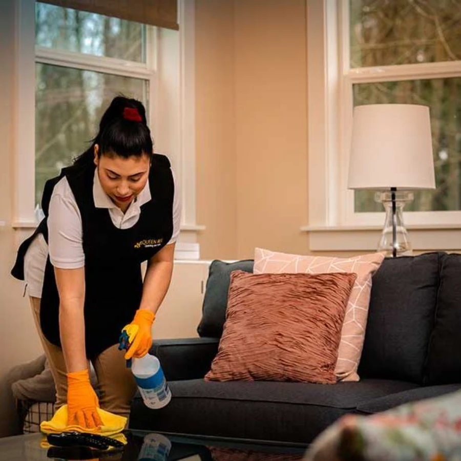 Maid cleaning coffee table with spray in residential home Fort Myers
